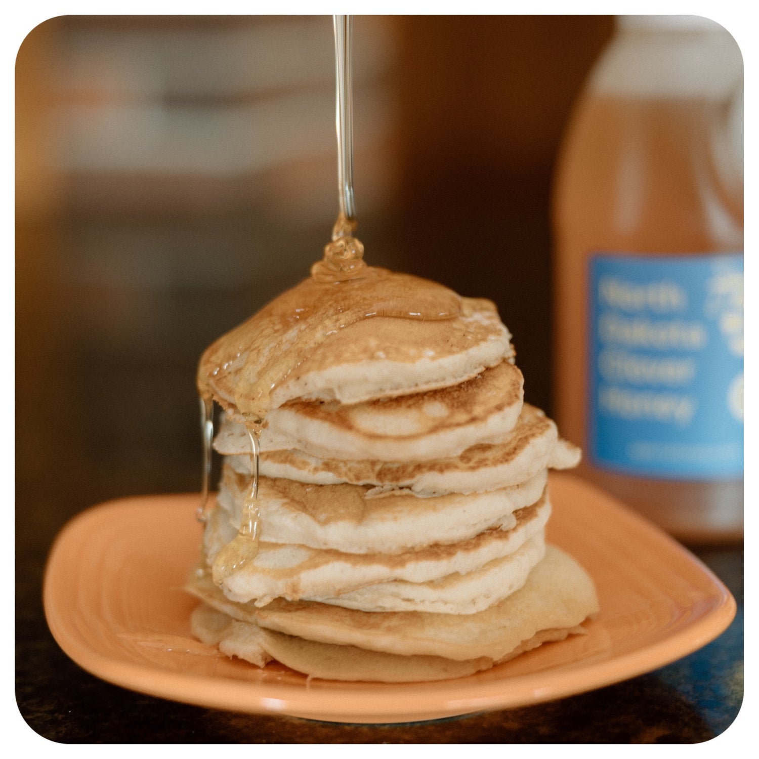 Clover honey being drizzled onto pancakes.