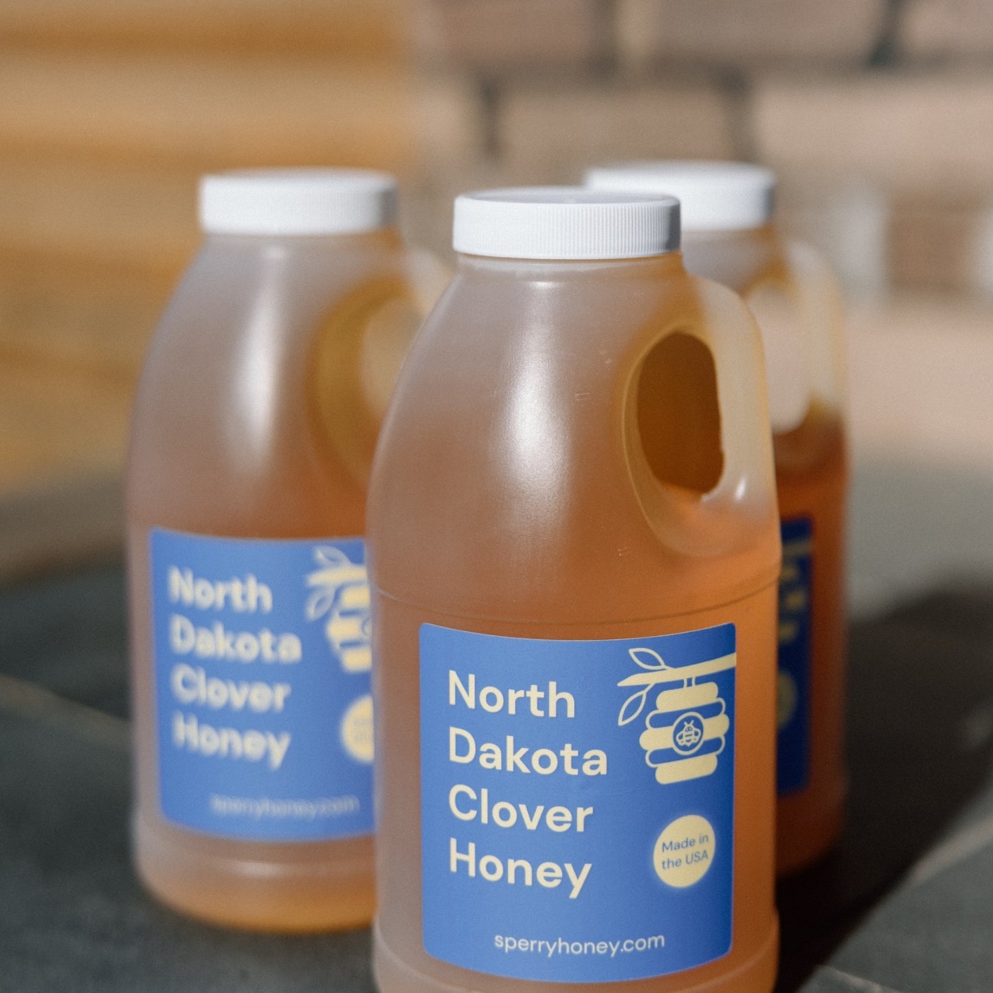 Three jugs of clover honey sitting in the sunshine.