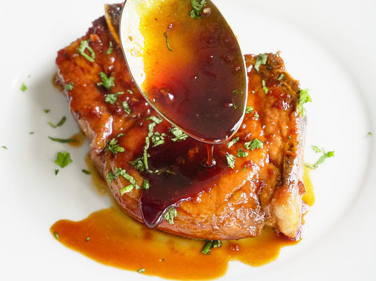 A spoon drizzling sauce over honey garlic pork chops.