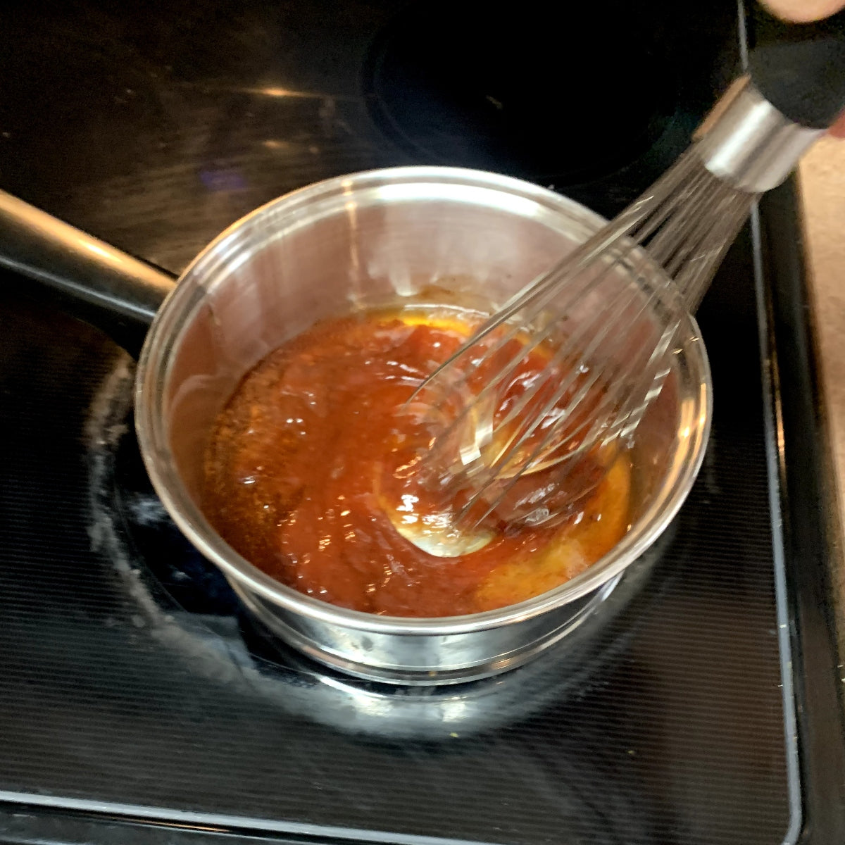 Whisking the ingredients for honey chipotle sauce in a saucepan.