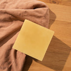 Yellow beeswax block on a wooden surface with brown fabric
