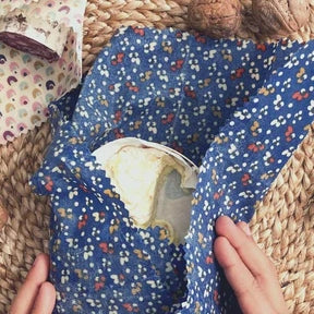 Person holding a blue floral-patterned bag with a woven surface underneath
