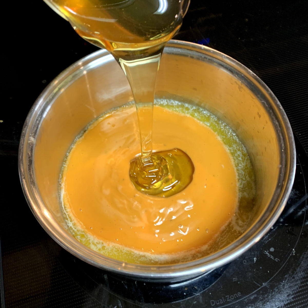 Pouring honey into a saucepan to make honey buffalo sauce.