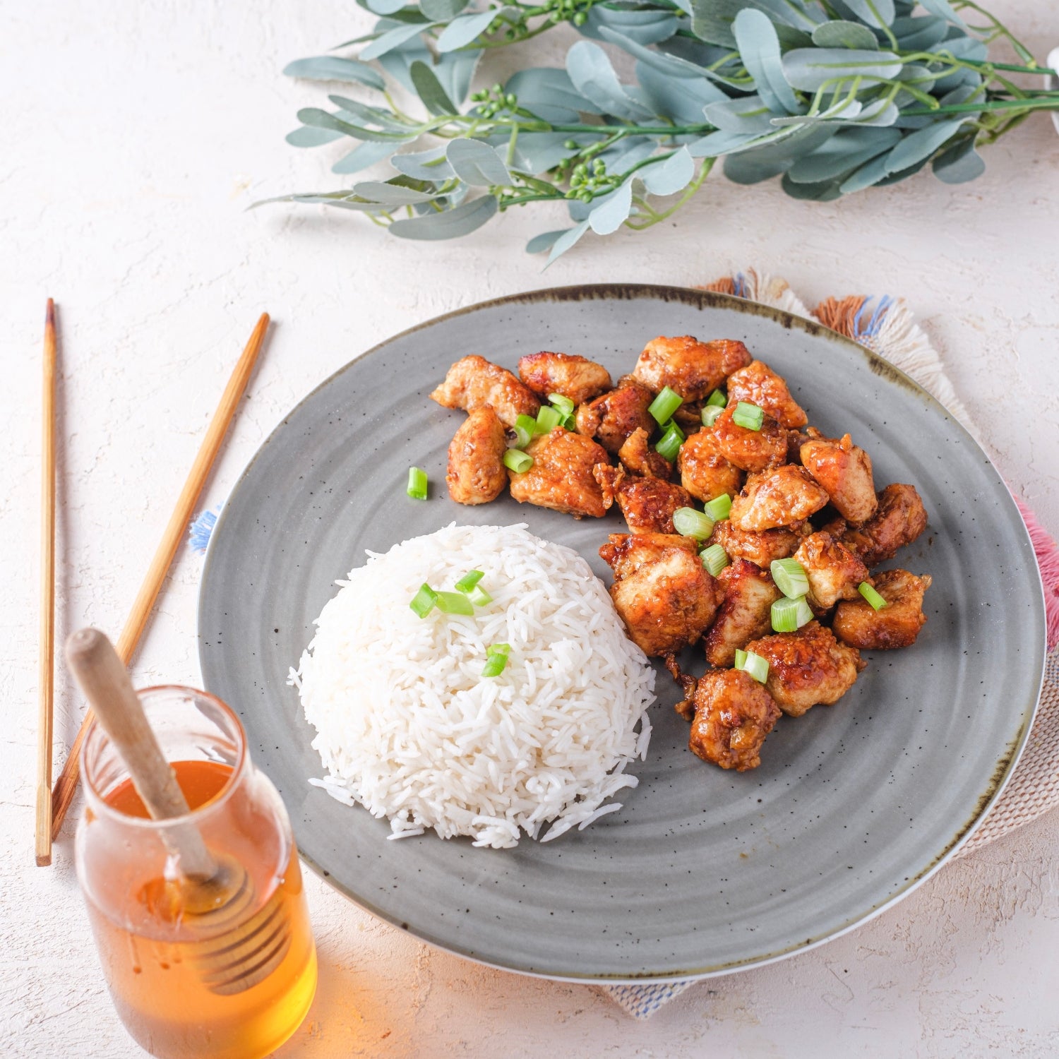 Honey chicken and rice on a plate and a jar of honey.