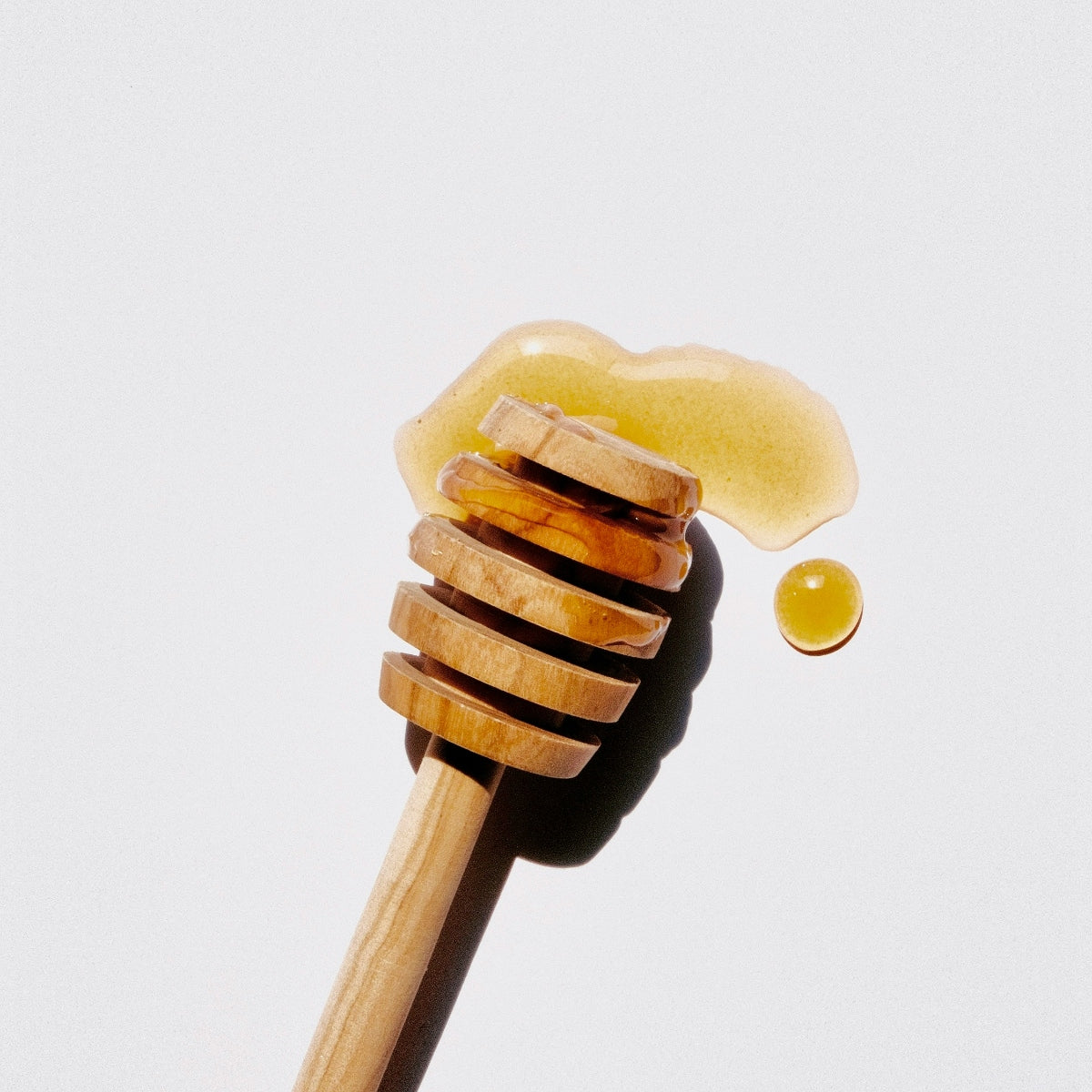A honey stick with some honey on a white background.