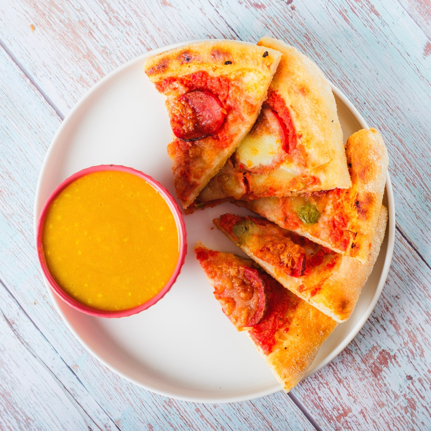 Honey mustard on a plate next to pizza.