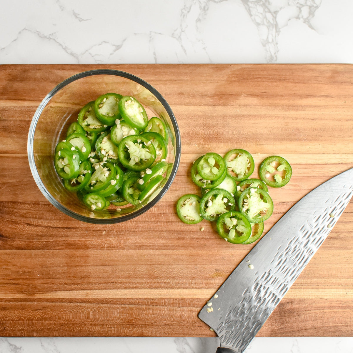 Jalapeño peppers being chopped on a cutting board.