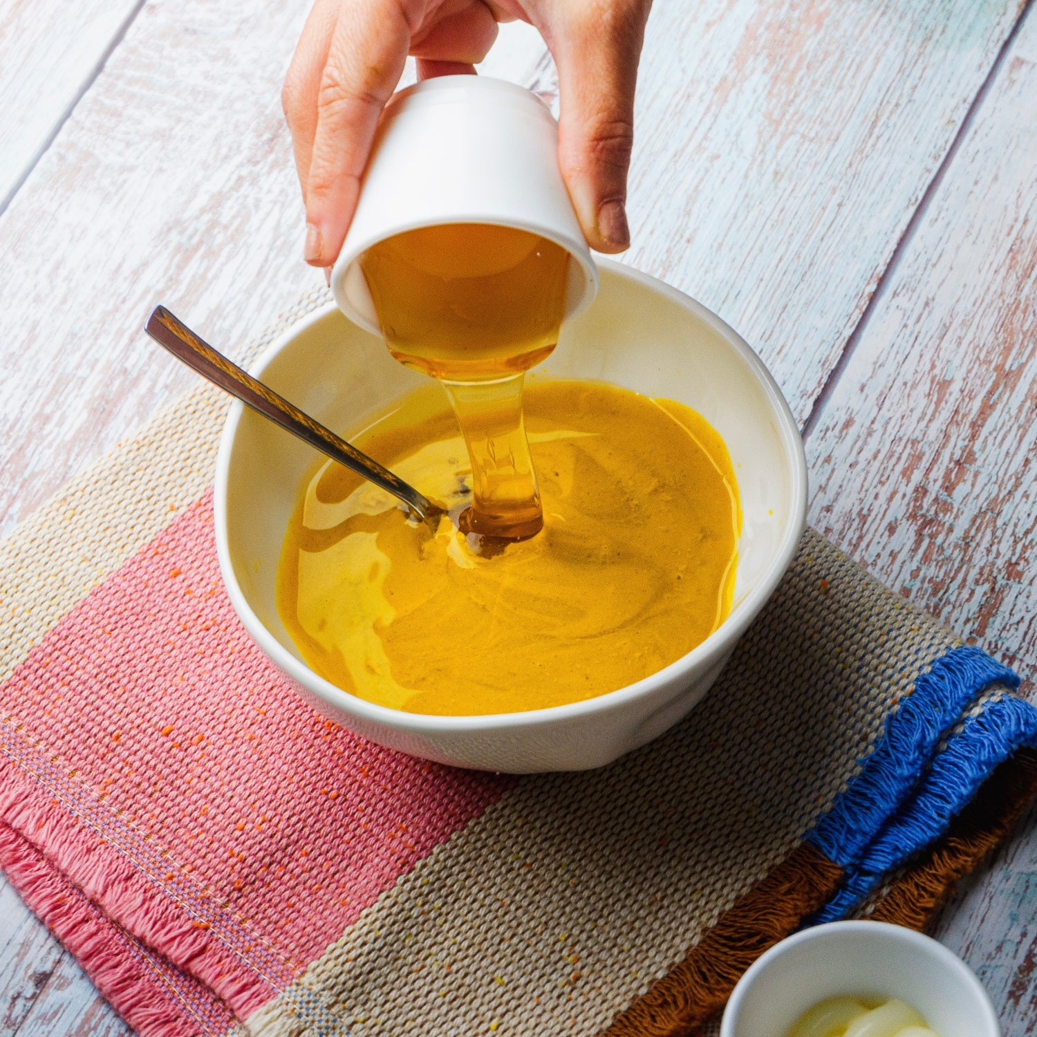 pouring honey into a bowl of honey mustard.