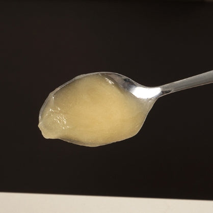 Spoon with a scoop of raw honey on a black background