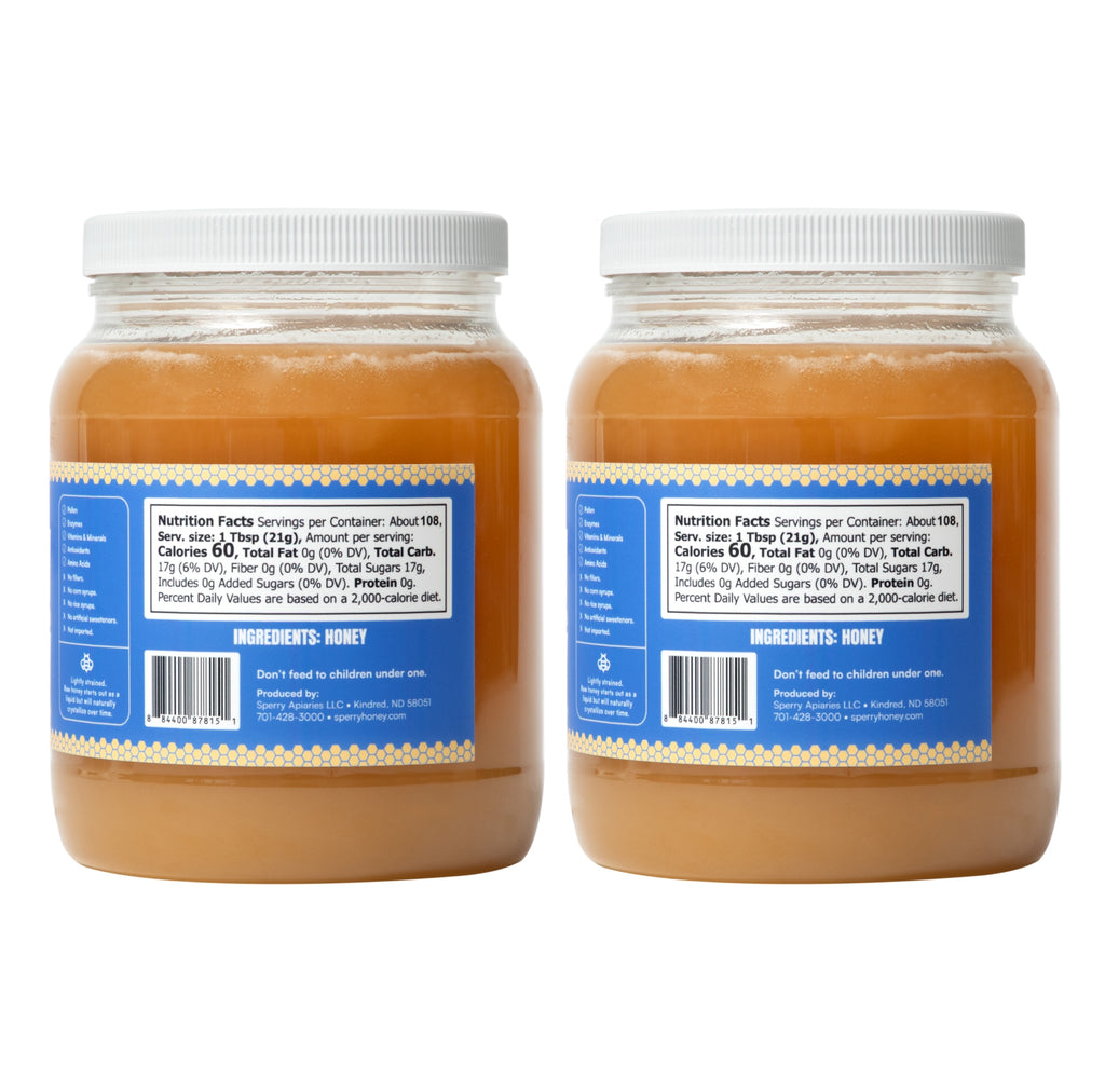 Two large jars of Raw & Unfiltered Honey with white lids and blue labels, shown side by side, facing backwards, on a white background.