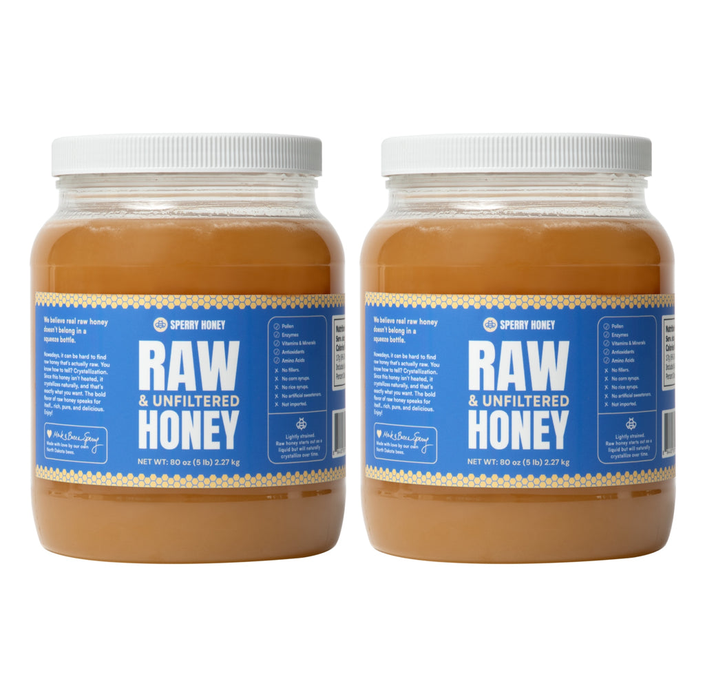 Two large jars of Raw & Unfiltered Honey with white lids and blue labels, shown side by side on a white background.