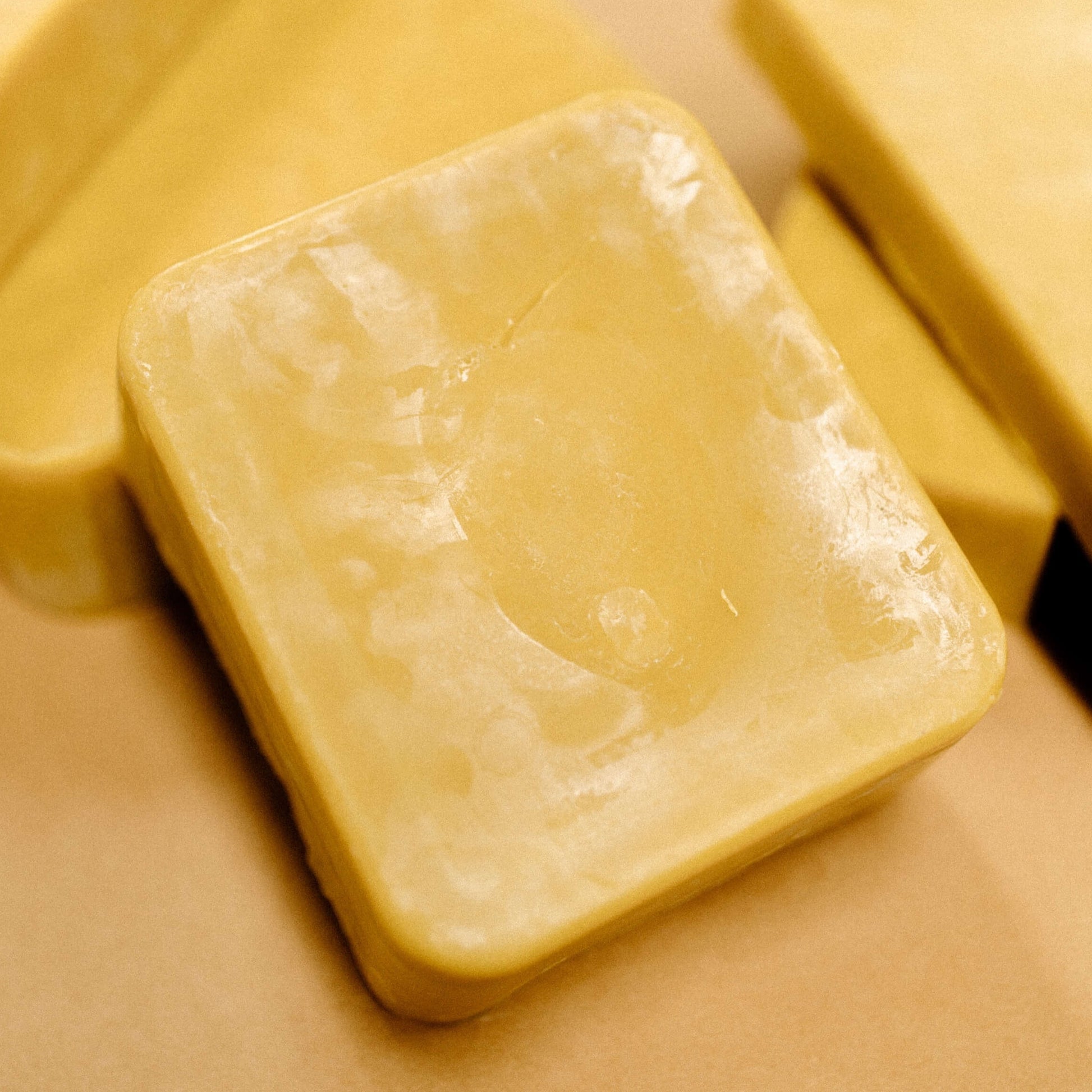 A yellow block of beeswax propped up against other blocks.
