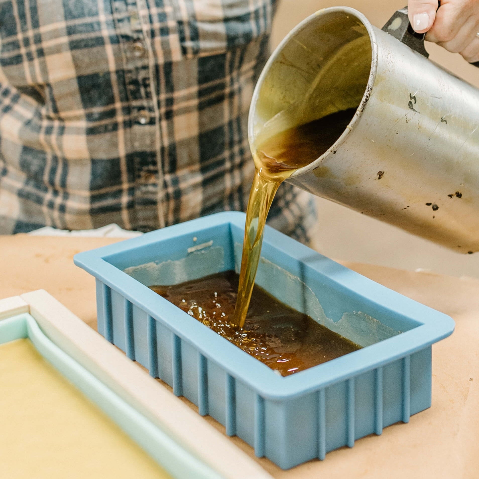 Another photo of Rebecca Sperry pouring the mold for a yellow block of beeswax.